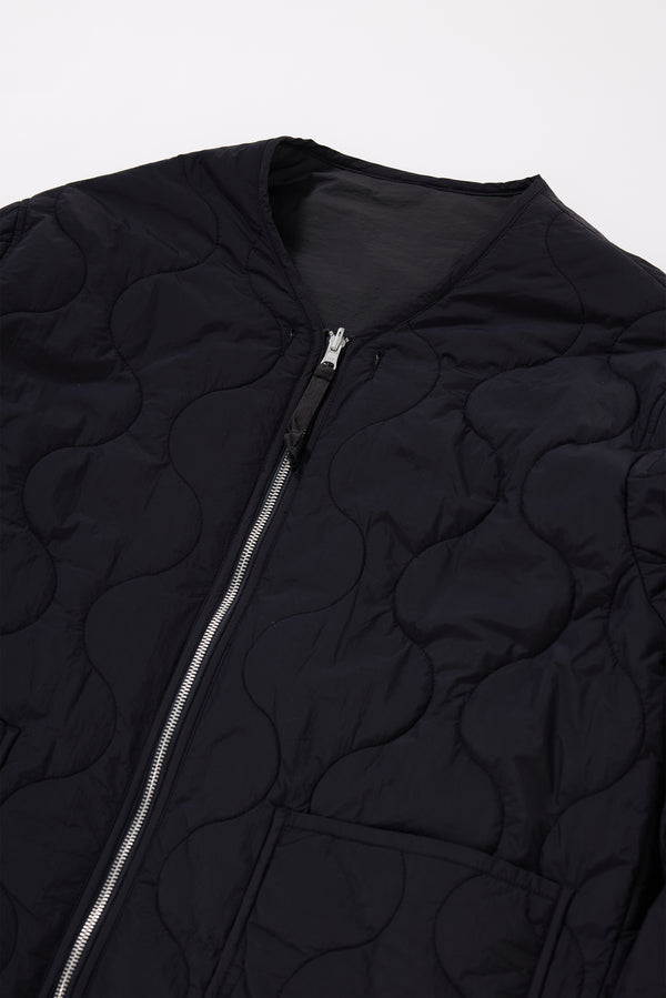 Close-up detail shot of ripple-patterned quilted stitching on vintage black recycled nylon reversible jacket. Showcasing Pocket, zip and cuff detailing. 