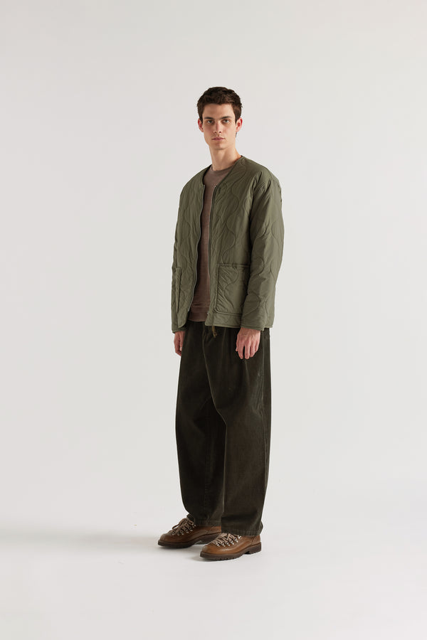 Front angle of the Olive Solstice Reversible recycled nylon jacket shown with ripple-patterned stitching facing outward and front pockets visible