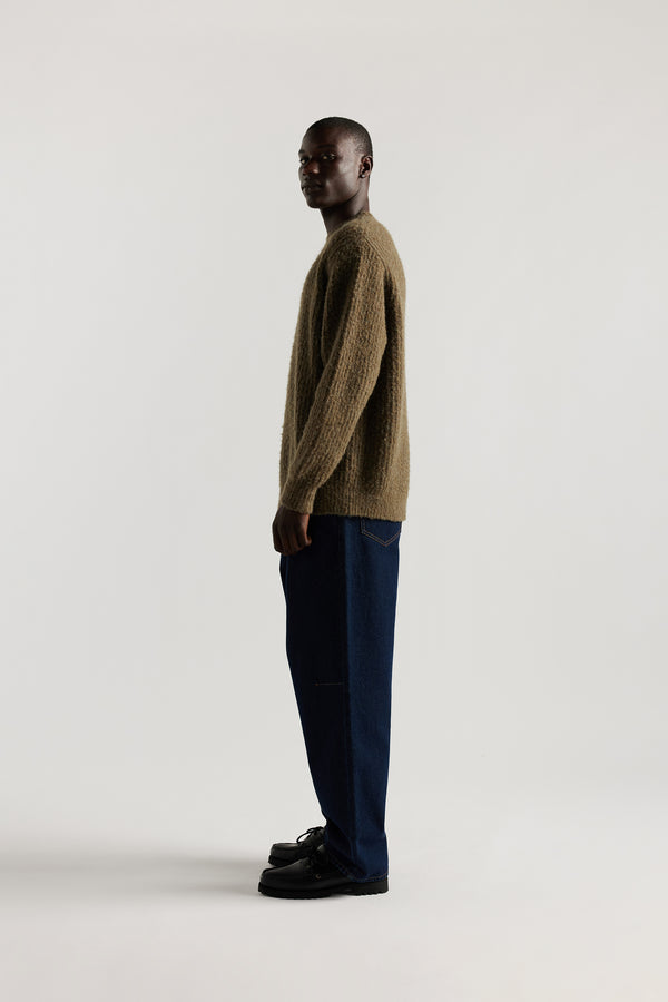 Side view of model in the Olive Spore Knit Sweater showing relaxed raglan silhouette and fluffy marle-flecked multi-directional rib knit texture