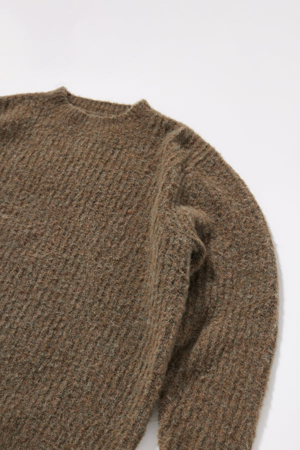 Close-up of exposed linking at the raglan seam on the Olive Spore Knit Sweater, a considered construction detail in fluffy alpaca blend