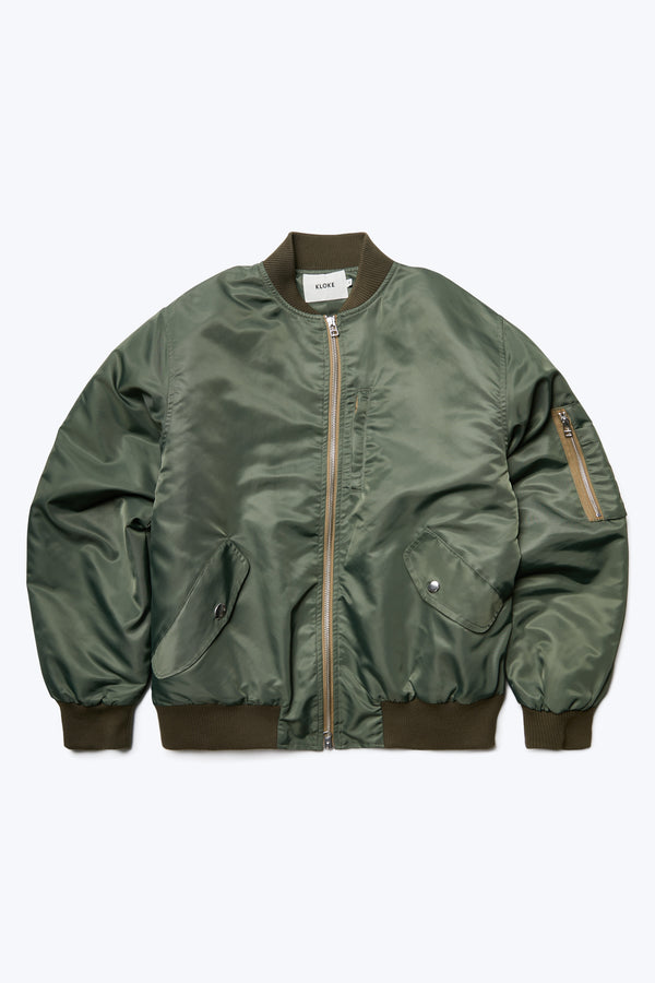 The Strata Bomber Jacket Olive Green is a  lightweight nylon jacket with quilted lining, double opening YKK hardware, rib trim and multiple pockets with zip and press stud closure. 