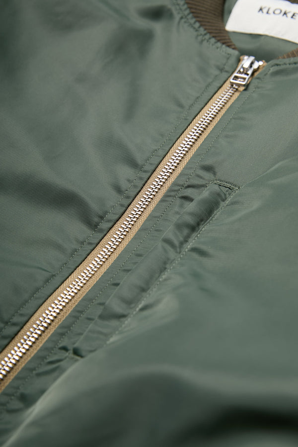 The Strata Bomber Jacket is a lightweight nylon jacket in Olive Green with double opening YKK hardware.