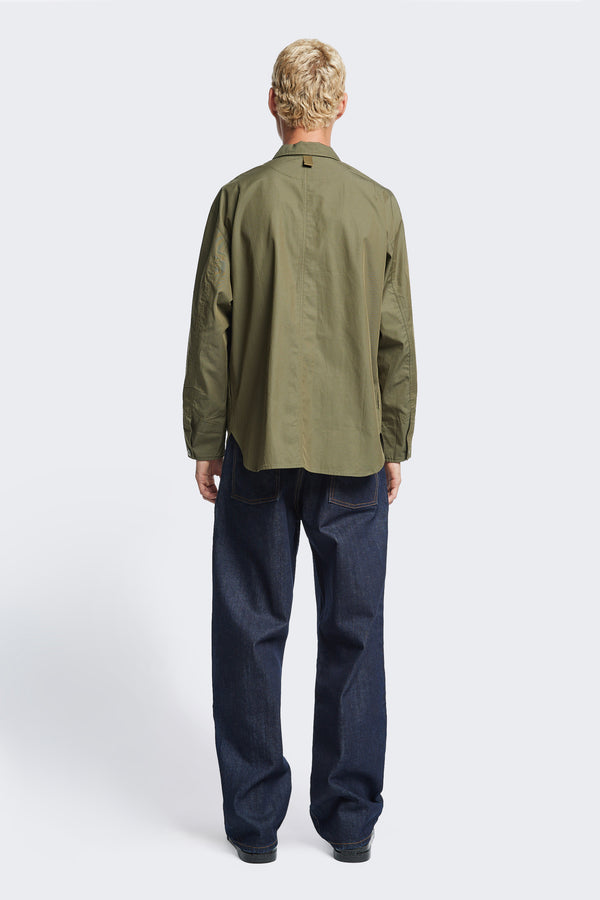 The back of the Territory Overshirt Olive, a military-inspired overshirt made from mid-weight cotton drill. Features shaped cuffs with button closure and cotton webbing detail at the back of neck.