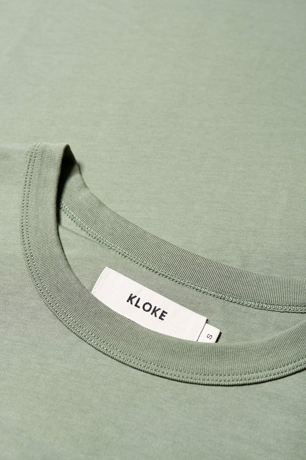 Close up fabric shot of The Oceania Tee is cut from a premium organic cotton jersey in Sage Green with a 1 x 1 rib bound cover stitched neckline. 