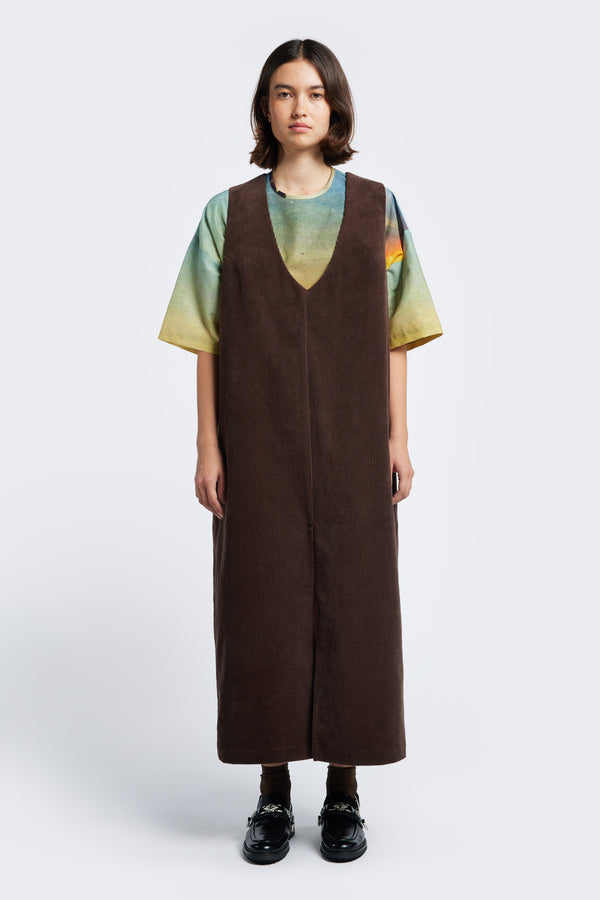 The Arc Dress, a full-length pinafore made from textured thick-wale corduroy in Dark Brown. 