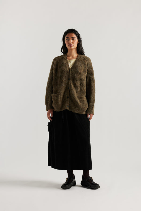 Female model in Olive Bloom Cardigan worn open and layered over a Tee and Skirt, showing relaxed oversized silhouette and fluffy alpaca blend texture