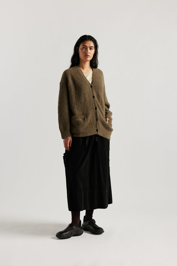 Female model in Olive Bloom Cardigan worn open and layered over a Tee and Skirt, showing relaxed oversized silhouette and fluffy alpaca blend texture