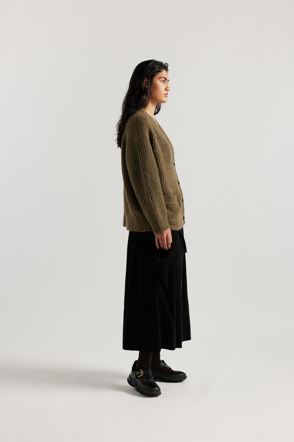 Female model in Olive Bloom Cardigan worn open and layered over a Tee and Skirt, showing relaxed oversized silhouette and fluffy alpaca blend texture