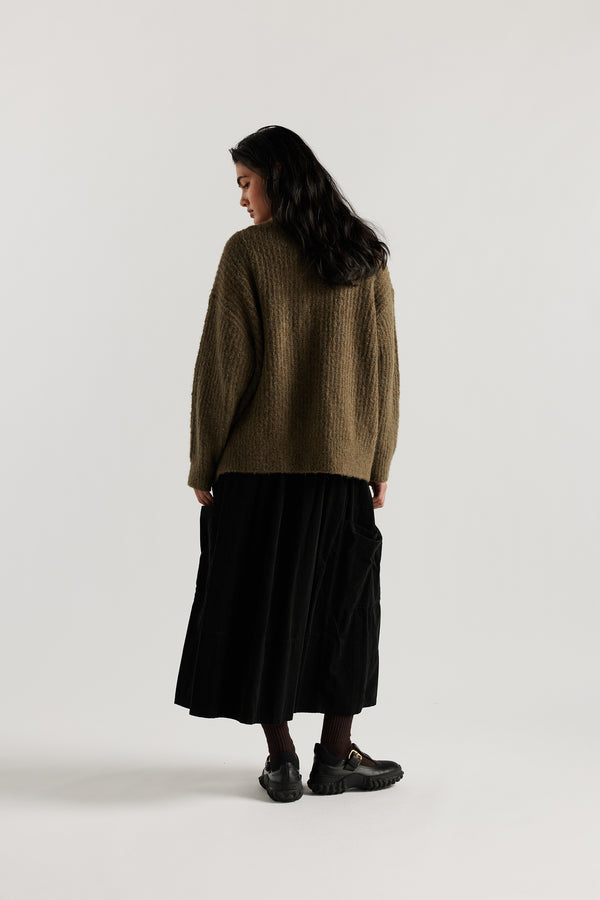Back of Female model in Olive Bloom Cardigan worn open and layered over a Tee and Skirt, showing relaxed oversized silhouette and fluffy alpaca blend texture