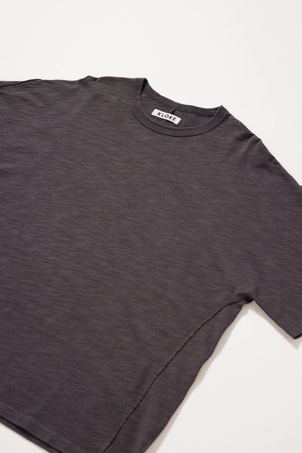 Close-up of the flat-lock seam detailing creating the twisted sleeve on the Black licorice  Overdyed Declare Tee.