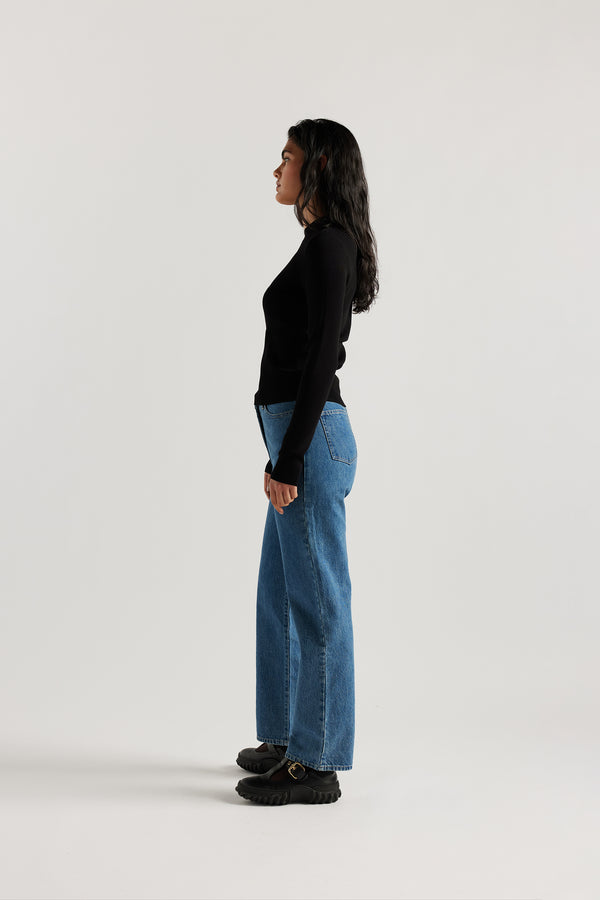 Model wearing straight-leg Evade jeans in mid blue premium Japanese denim with slightly higher rise and flattering fit