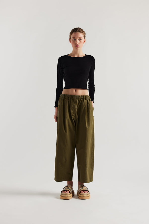 Front view of the model in the Factor Pleat Pant Olive Green. A relaxed silhouette defined by an encased elastic waistband. 