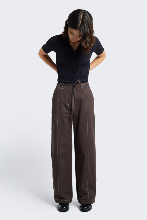 Model wears the Found Tie Front Pant Brown, a relaxed, straight-leg pant with belt loops and waist tie. Crafted from a durable cotton that’s easy to wear. Complete with white contrast topstitch and diagonal seam pockets at the front.