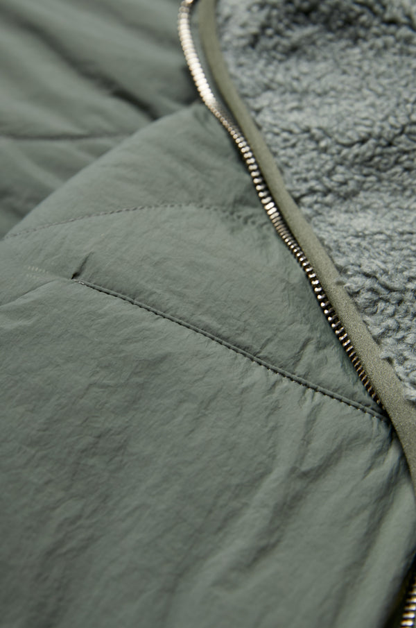 Close up of the fabric for the Hearth Shearling Reversible Vest Petrol Green with faux shearling fabrication and the reverse in a recycled nylon. 