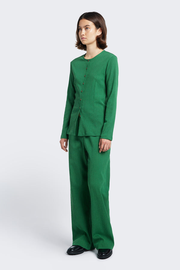 The Hideout Crinkle Top Green, a slim fit top made from a special crinkle fabric. This top has a darted waistline and straight hem and features a centre front button through and round crew neckline. Styled with the Oracle Pant Green.