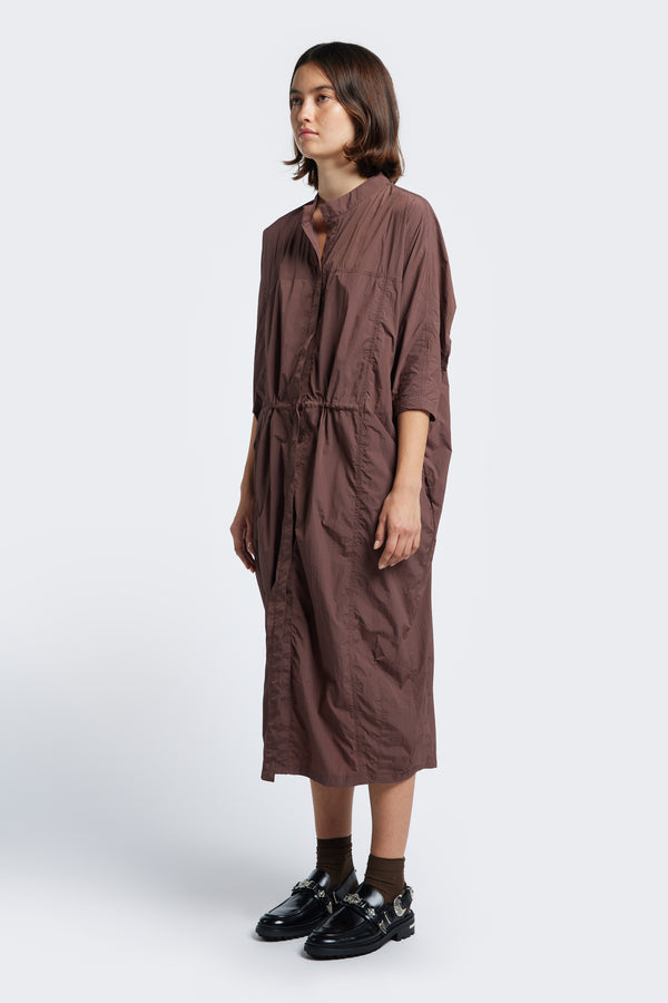 The Infra Dress Cocoa is a lightweight dress made from Nylon and features seam details, a round neckline, dropped shoulders and pull ties at waist to adjust the fit to your liking. The centre button-down opening allows you to wear the dress open as an layering piece. 