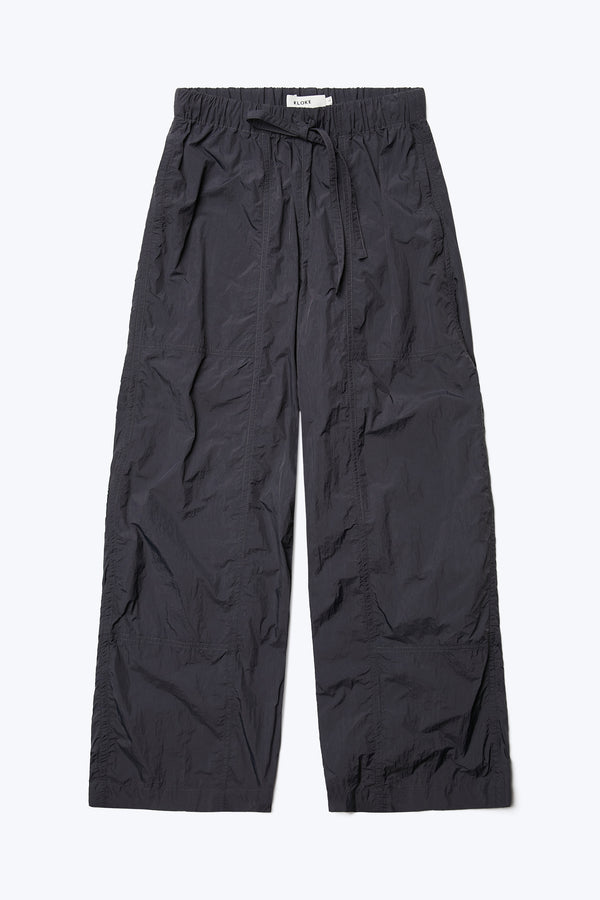 The front of the Inland Pant Black, a  loose fit pant seam detail running down the front of the leg for texture. Featuring an elasticated waistband with tie and in seam side pockets. Made from 100% Nylon. 