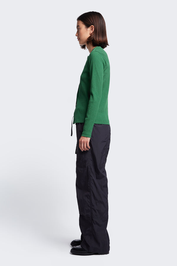 Side profile of the Inland Pant Black, a light, loose fit pant made from 100% Nylon and seam detail running down the front of the leg for texture. 