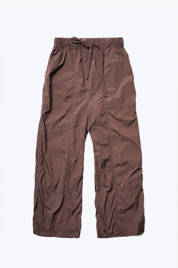 The front of the Inland Pant Cocoa, a light, loose fit pant seam detail running down the front of the leg for texture. Featuring an elasticated waistband with tie and in seam side pockets. Made from 100% Nylon. 