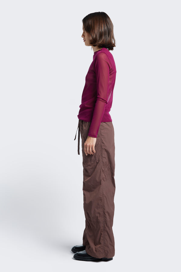 Side profile of the Inland Pant Cocoa, a light, loose fit pant made from 100% Nylon and seam detail running down the front of the leg for texture. 