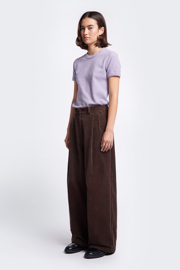 The Interim Cord Pant Dark Brown, a semi-tailored cord pant with a generous and flattering double-pleated fit. Featuring side slant-pockets and two button-closing back pockets to keep valuables safe.