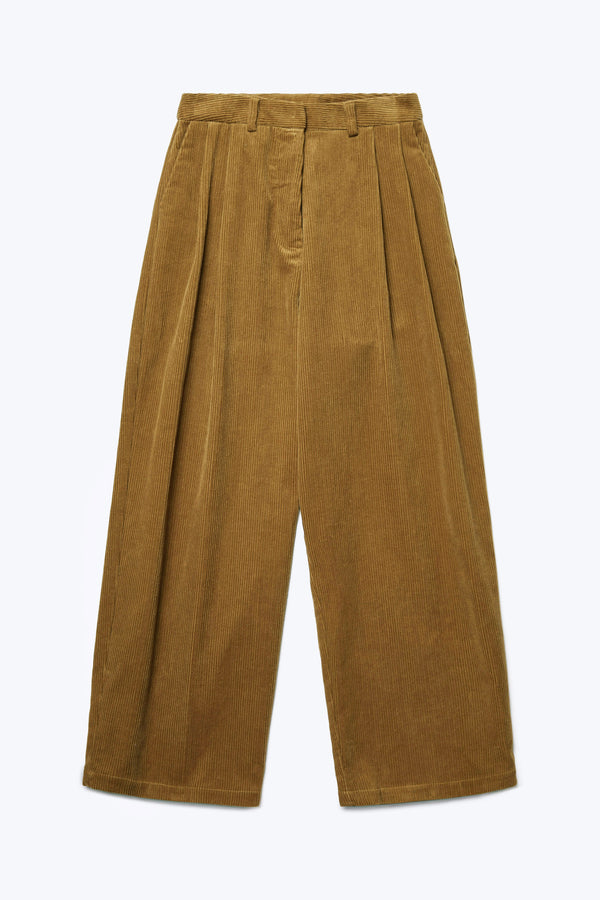 The front of the Interim Pant Golden Tan, a semi-tailored cord pant with a generous and flattering double-pleated fit. Featuring side slant-pockets and two button-closing back pockets to keep valuables safe. 