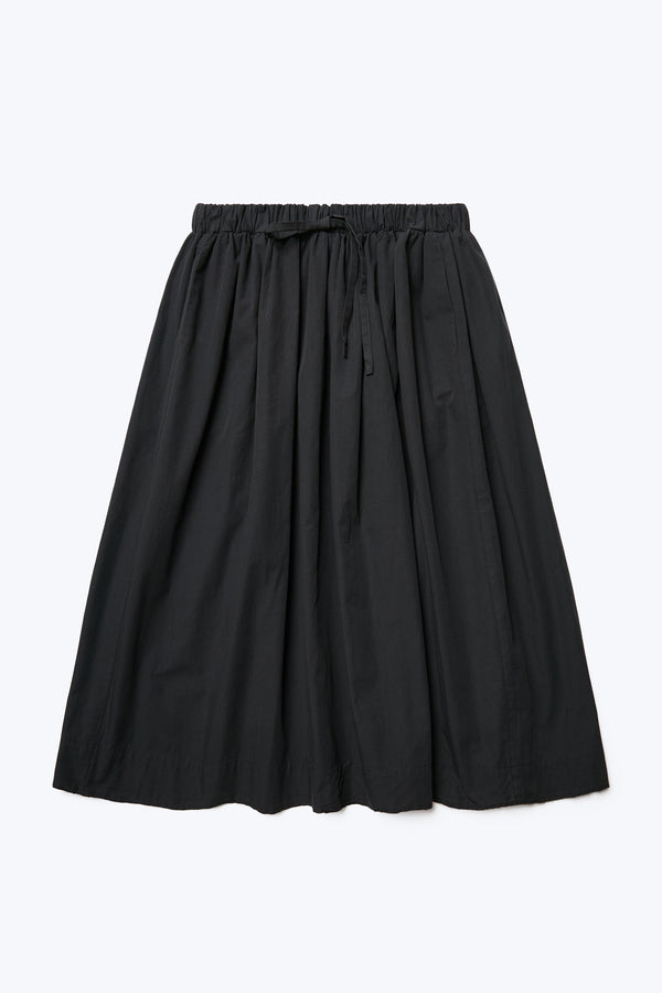 The front of the Interlude Skirt Black a full gathered skirt with an elasticated waist, two front welt pockets and raw hem. Available in five sizes. 