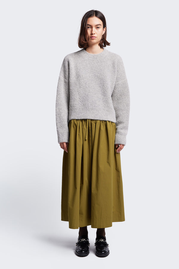 The Interlude Skirt in Moss Green, is a mid-length, full gathered skirt with an elasticated waistband with centre front self tie, two front welt pockets and raw hem. Made from 100% cotton. 