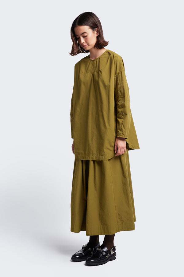 The Interlude Skirt Moss Green, a mid-length, full gathered skirt with a raw hem. Styled with the Plateau Blouse Moss Green. 