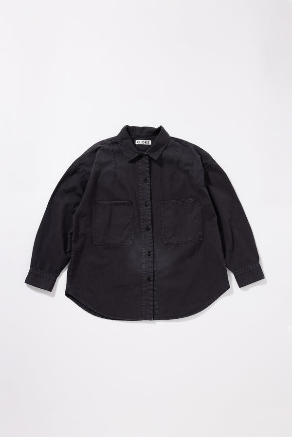 Flat front of the black fade Iris Denim Shirt with an oversized fit, dropped shoulders and utility-inspired chest pockets.