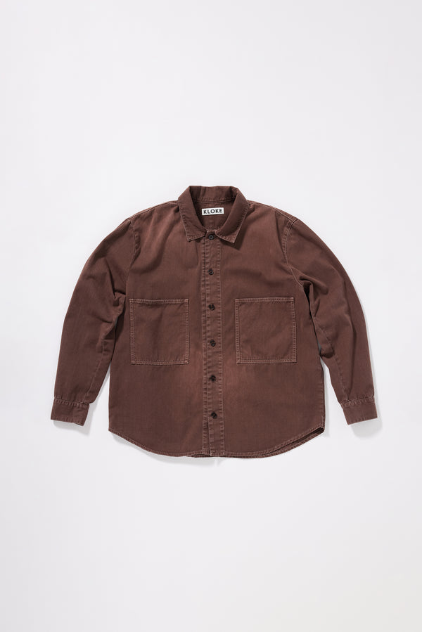 Flat front of the Brown Fade Iris Denim Shirt with an oversized fit, dropped shoulders and utility-inspired chest pockets.