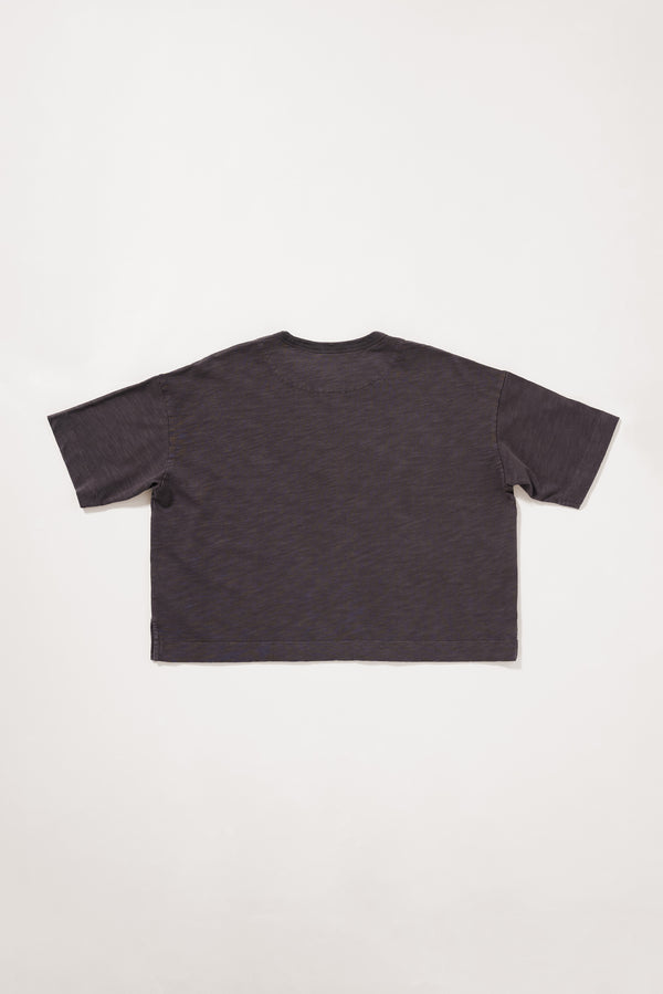 Flat Back view of the black Obelisk Tee showing the relaxed boxy silhouette.