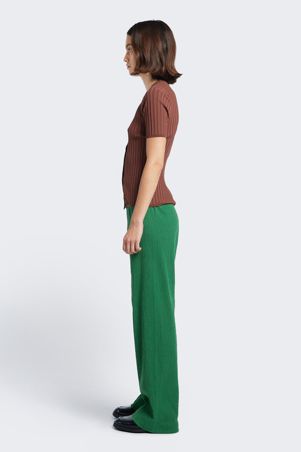 Side profile of the Oracle Crinkle Pant, a straight leg pant with an elasticated waistband. Made from a special crinkle fabrication in green. 