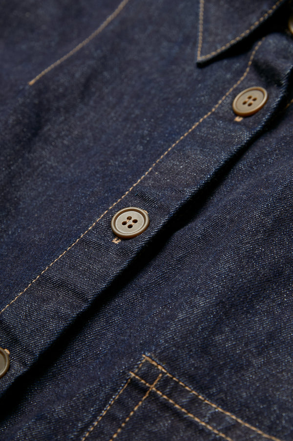 The centre front button detail on the Recess Denim Shirt. Crafted from Japanese denim with contrast topstitch.