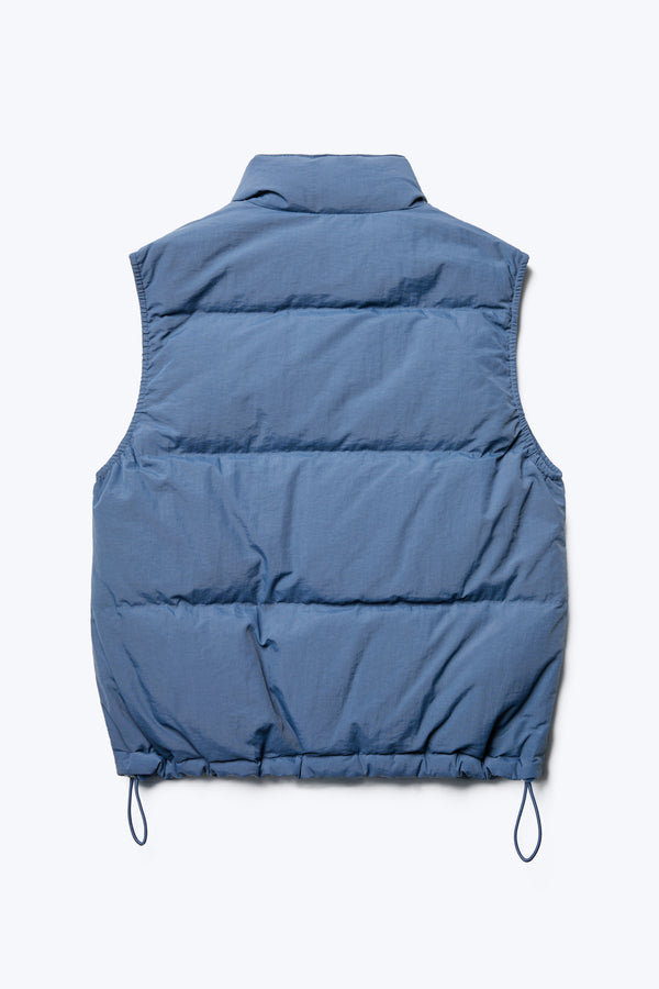 The back of the Stay Quilted Vest Blue is a quilted down puffer vest with high neckline, elasticated armholes for comfort and elastic waist pulls with toggles. Made from 100% Recycled Nylon, Lining 100% Recycled Nylon, 100% Post Consumer Down Fill.
