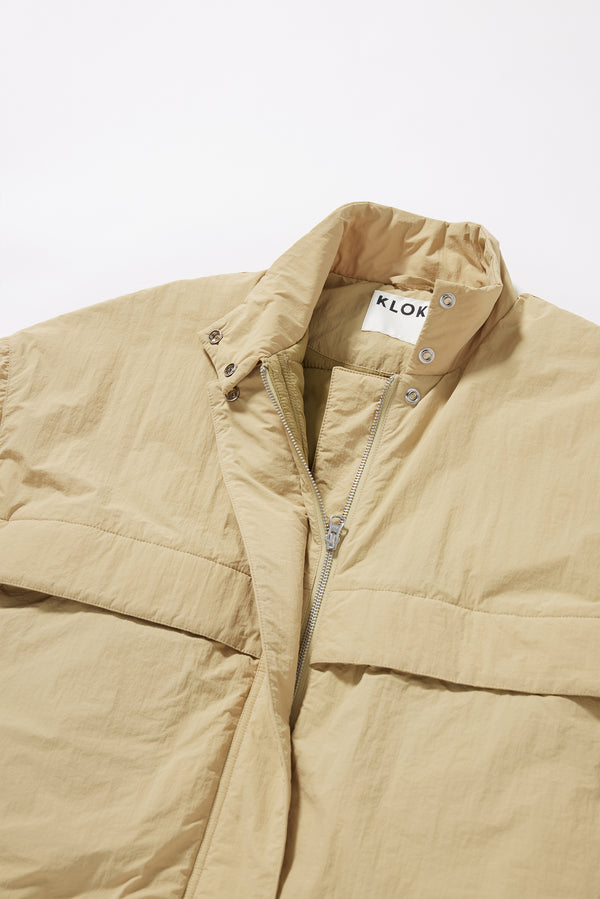Close-up of military-style tab collar on the sand beige Surge Quilted Jacket