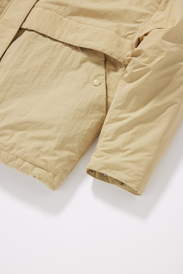 Close-up of button pocket and cuff details on the sand beige Surge Quilted Jacket