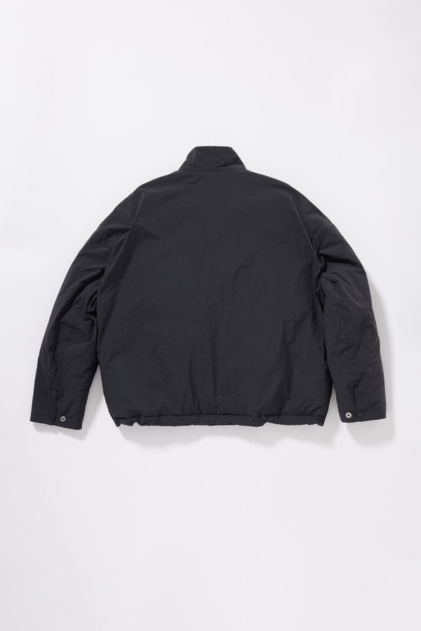 Flat black of Surge Quilted Jacket showing dropped shoulders, gently sculpted sleeves and relaxed quilted silhouette