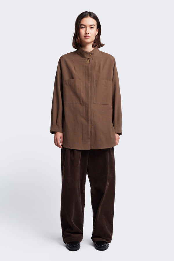 The Tenet Blouson Shirt is a long sleeve shirt with a relaxed silhouette, high stand collar with button closure and two front patch pockets at the chest. Made from a textural cotton fabric in brown. 