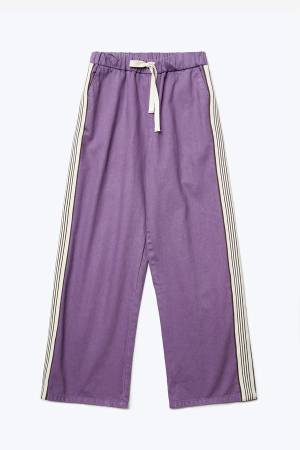 Flat lay of the front of the Tribute Side Trim Pant Purple. These casual wide leg pants have an elasticated waist with tie and front and rear patch pockets. Finished with side stripe trim detail.