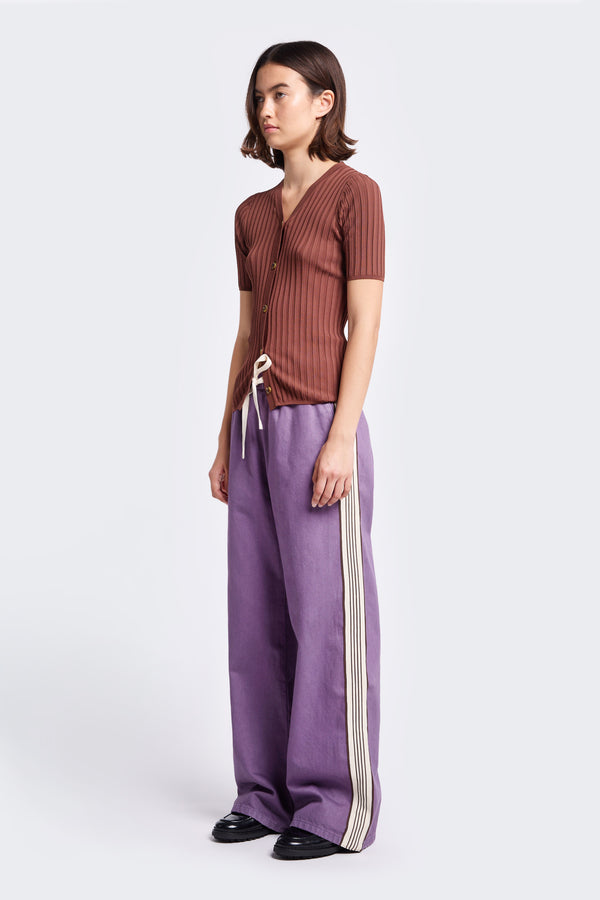 The Tribute Side Trim Pant is wide-leg pant in softened cotton in Purple. Finished with a side stripe time detail and elastic waist with tie-front.