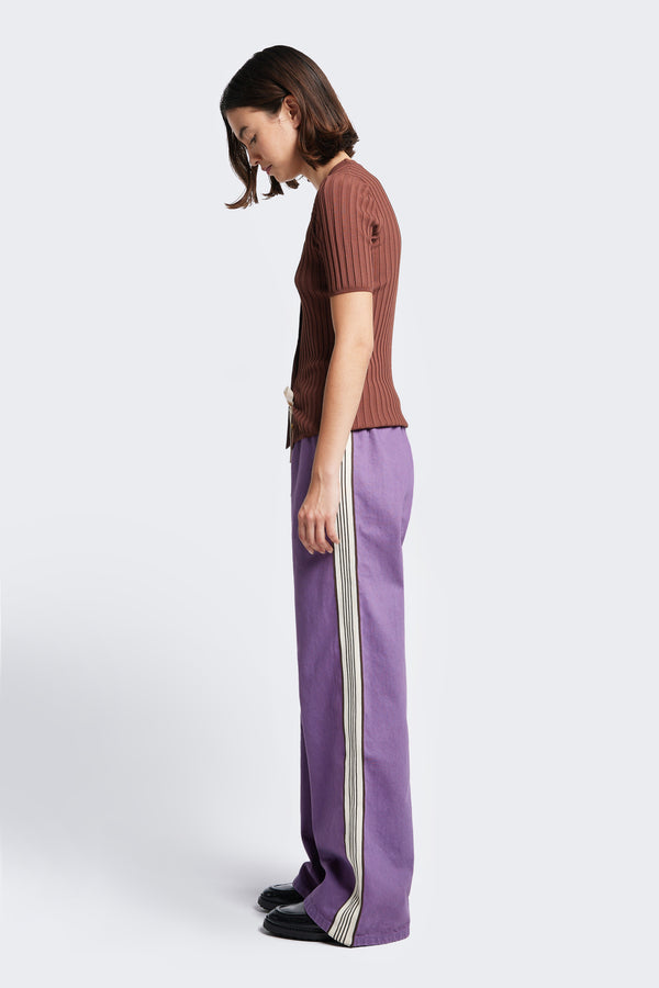 Side profile of the Tribute Side Trim Pant with stripe trim detail. Made from softened cotton in Purple. Features side and rear pockets. 