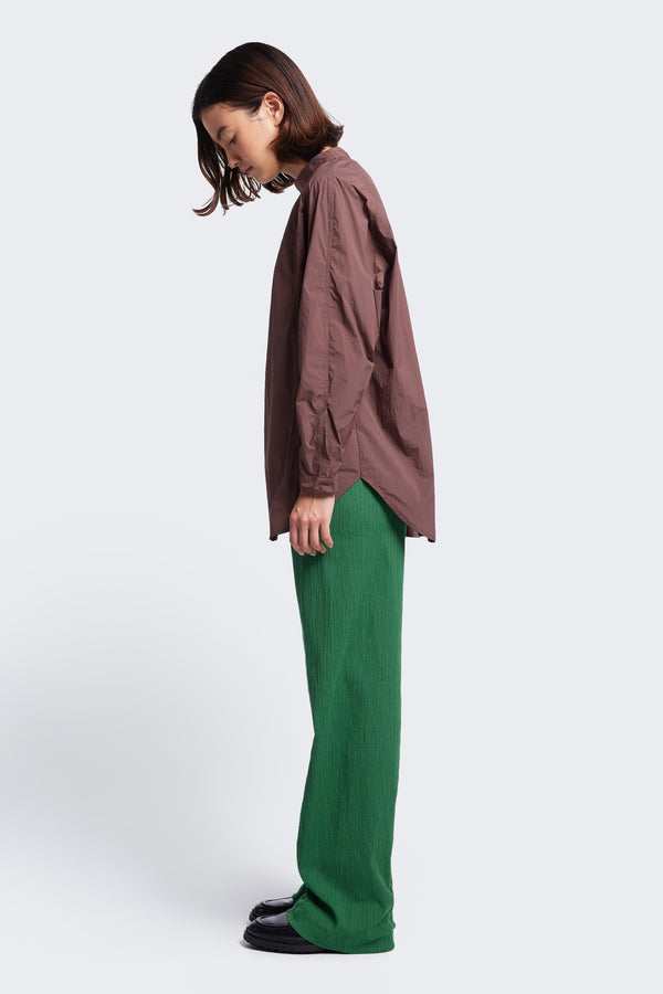 Side profile of the Women's Waking Blouse Cocoa, a relaxed style shirt with a stand collar with centre back button opening, dropped shoulders and a hem cuff with button opening. This parachute style shirt is made from 100% nylon. 