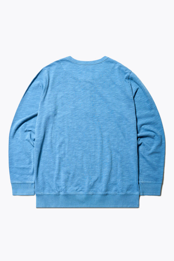 Back of The Asperse Henley in Blue, featuring a three-button placket, ribbed cuffs and hem, and a garment pigment-dyed finish. Available in 5 sizes. 