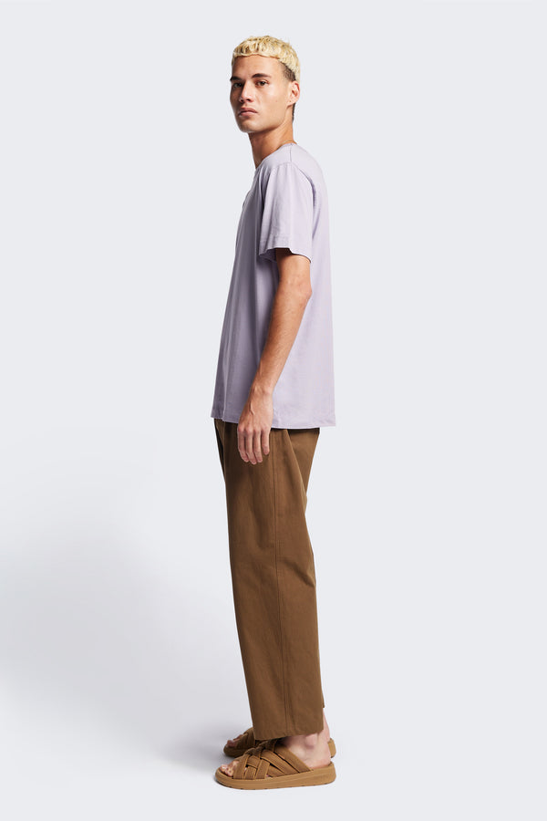 Side of The Boulder Pleat Pants in Brown, crafted from cotton herringbone twill, featuring side slant pockets, back patch pockets, and an elastic waistband with internal pull. Available in 5 sizes. 