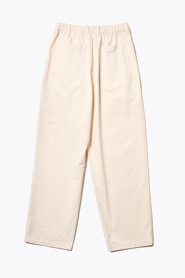 Back of The Boulder Pleat Pants in Chalk Beige, crafted from cotton herringbone twill, featuring side slant pockets, back patch pockets, and an elastic waistband with internal pull. Available in 5 sizes. 