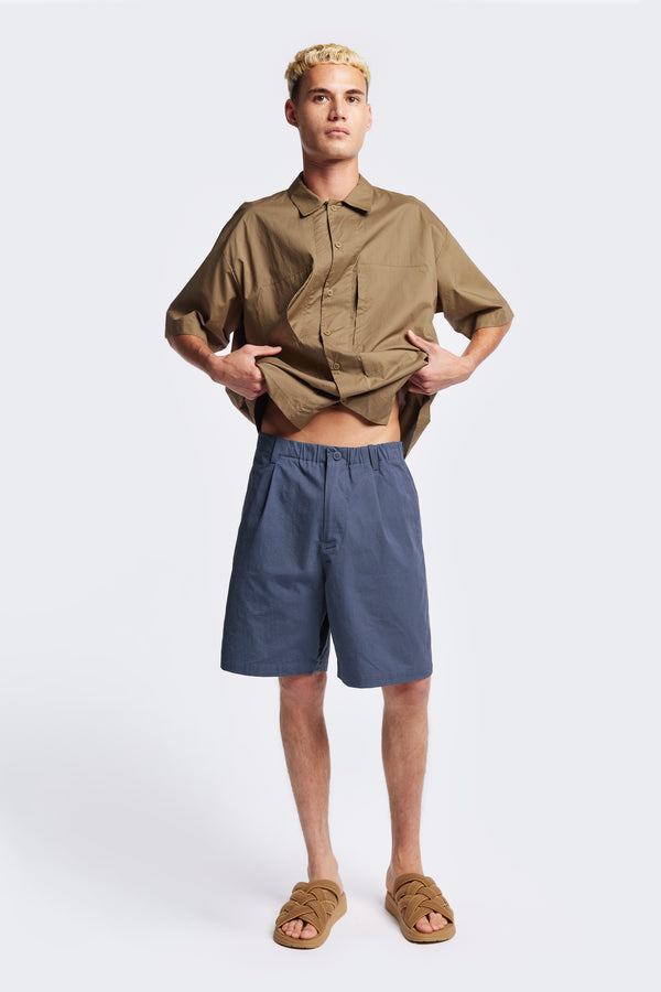 The Degree Pleat Short, a laidback and adaptable easy to weather summer short. Crafted in a blue washed cotton herringbone twill. Available in 5 sizes. 