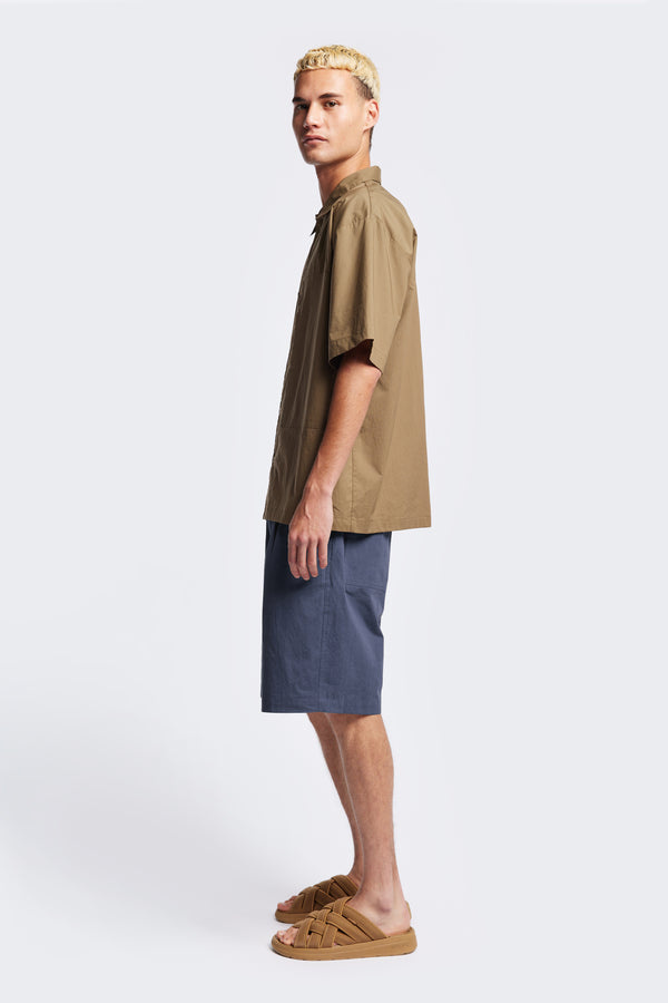 Side of the Degree Pleat Short, a laidback and adaptable easy to weather summer short. Crafted in a blue washed cotton herringbone twill. Available in 5 sizes. 