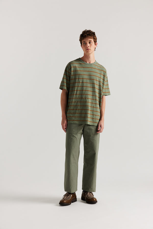 Front view of male model in Olive Lenz Pant with straight-leg silhouette, front patch pockets and twin-needle topstitch detail.