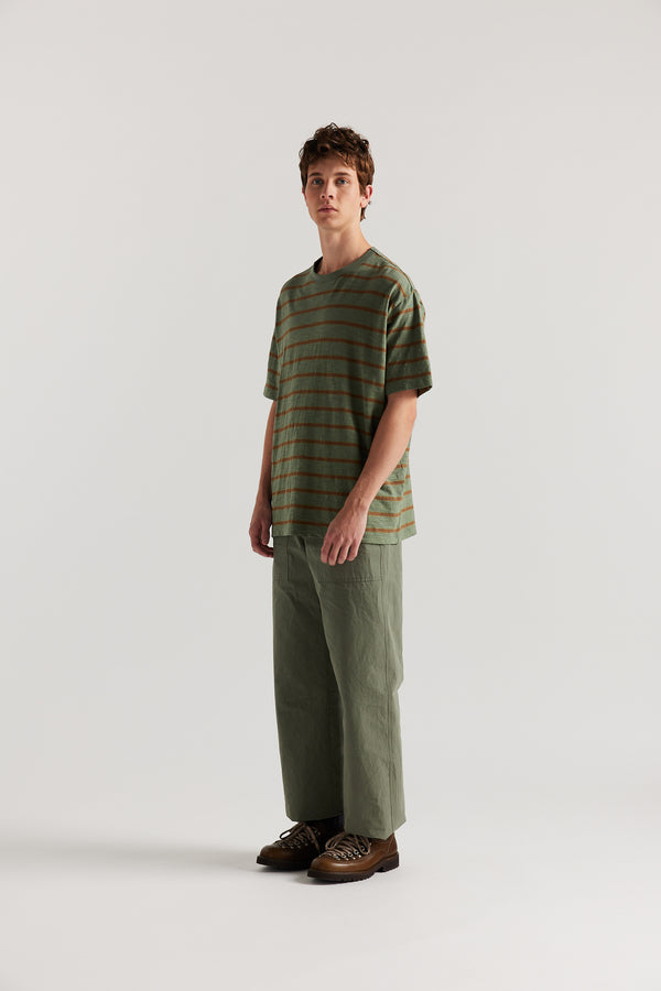 Front view of male model in Olive Lenz Pant with straight-leg silhouette, front patch pockets and twin-needle topstitch detail.